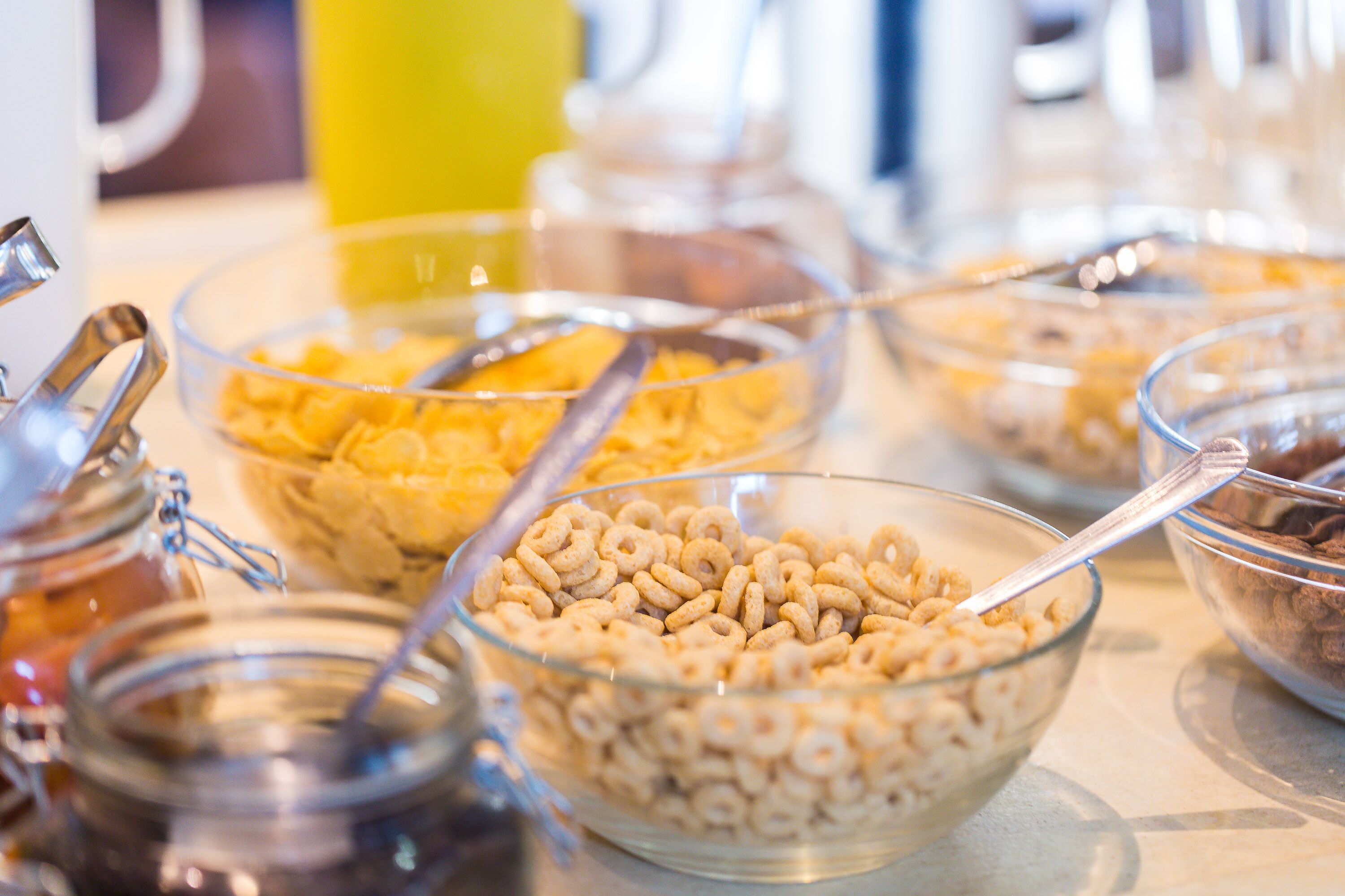 A buffet with various food items including cereal and sauces in glass bowls.