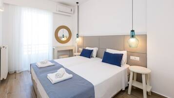A hotel room with a large bed, two bedside tables, a round mirror, and a small stool.