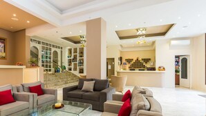 A spacious lobby with a modern design, featuring a seating area with sofas and armchairs, a glass coffee table, and a staircase leading to upper floors. - Eltina Hotel (Rethymno)