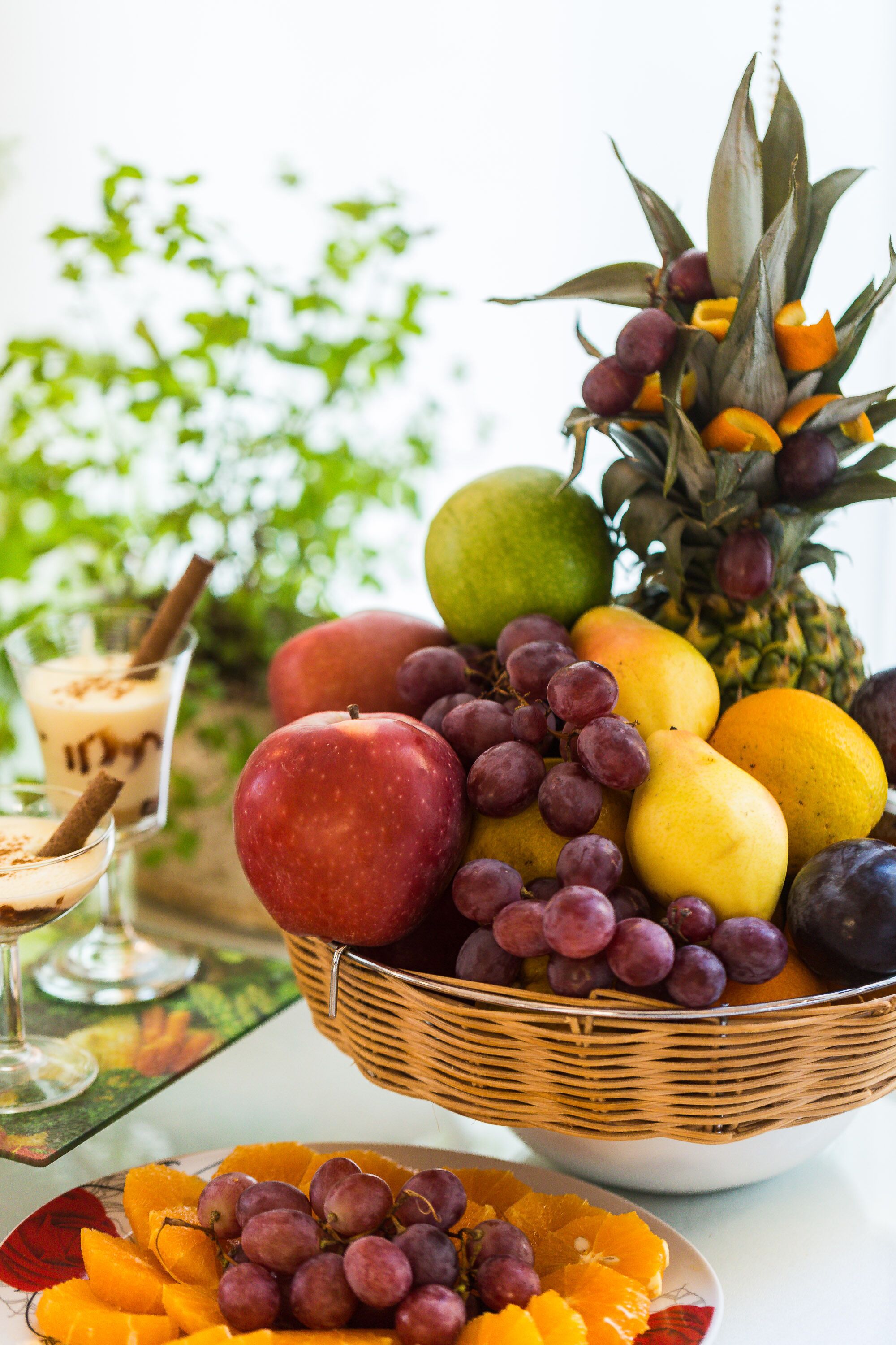 Un cesto di frutta con mele, uva, arance e un ananas.