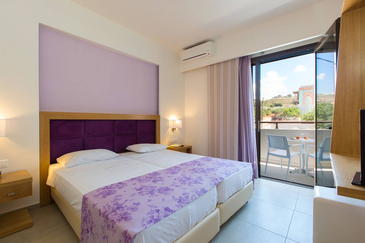 Une chambre d’hôtel avec un grand lit, une table de chevet, une fenêtre avec des rideaux et une vue sur l’extérieur.