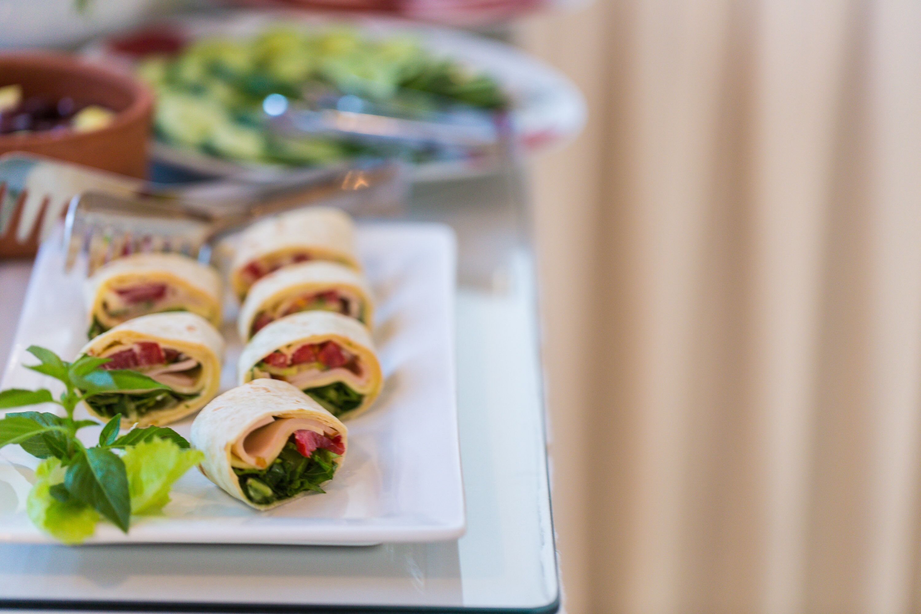 Une assiette de sandwichs roulés garnis de laitue et d'autres ingrédients.