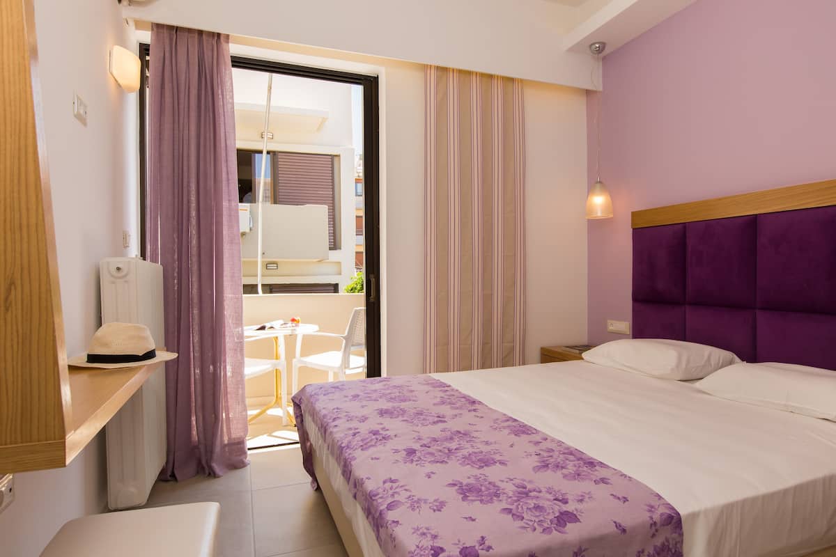 Une chambre d’hôtel avec un lit, un petit bureau, une chaise, une fenêtre avec des rideaux et une vue sur l’extérieur.