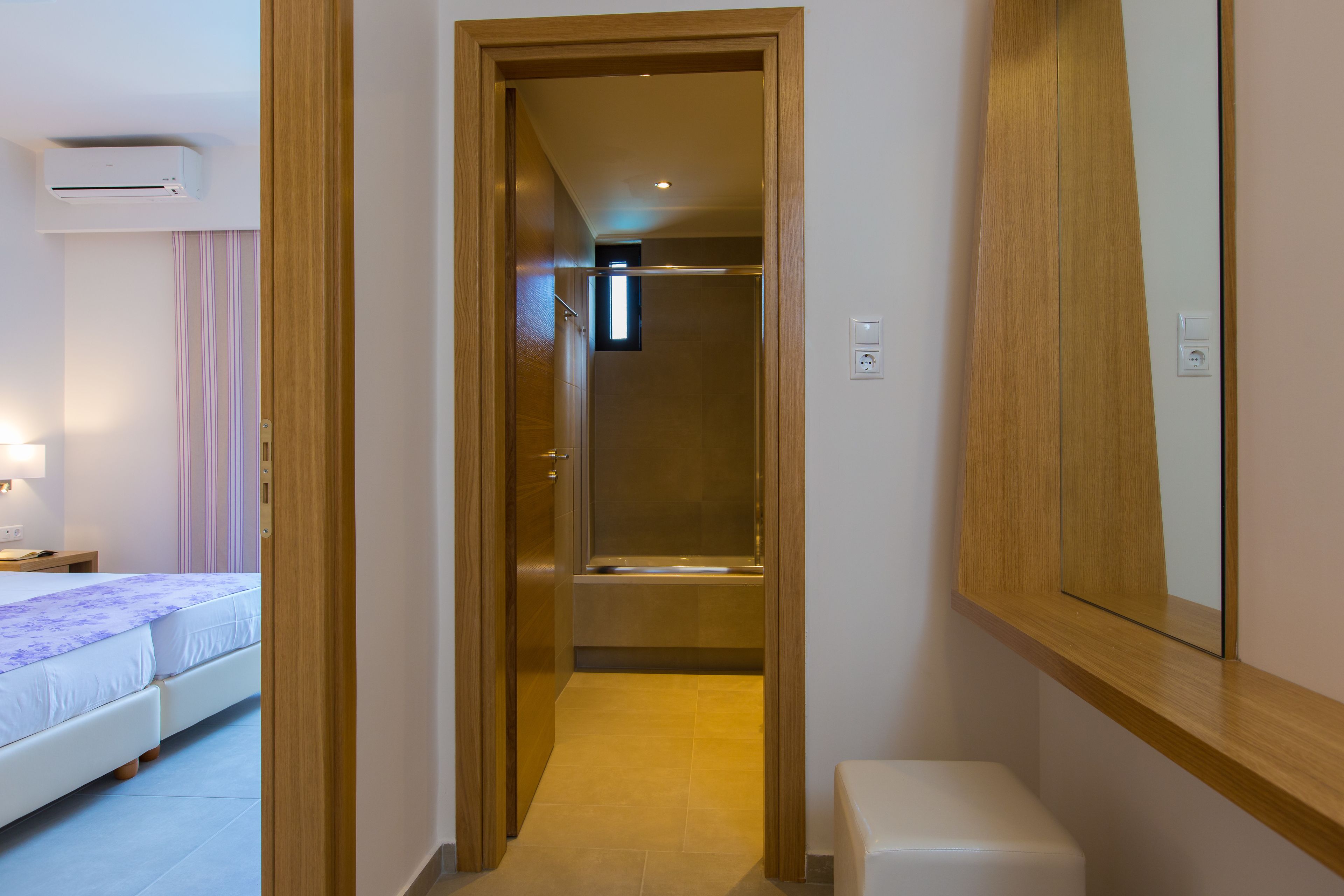 A hotel room with a bed, bedside table, and a mirror.