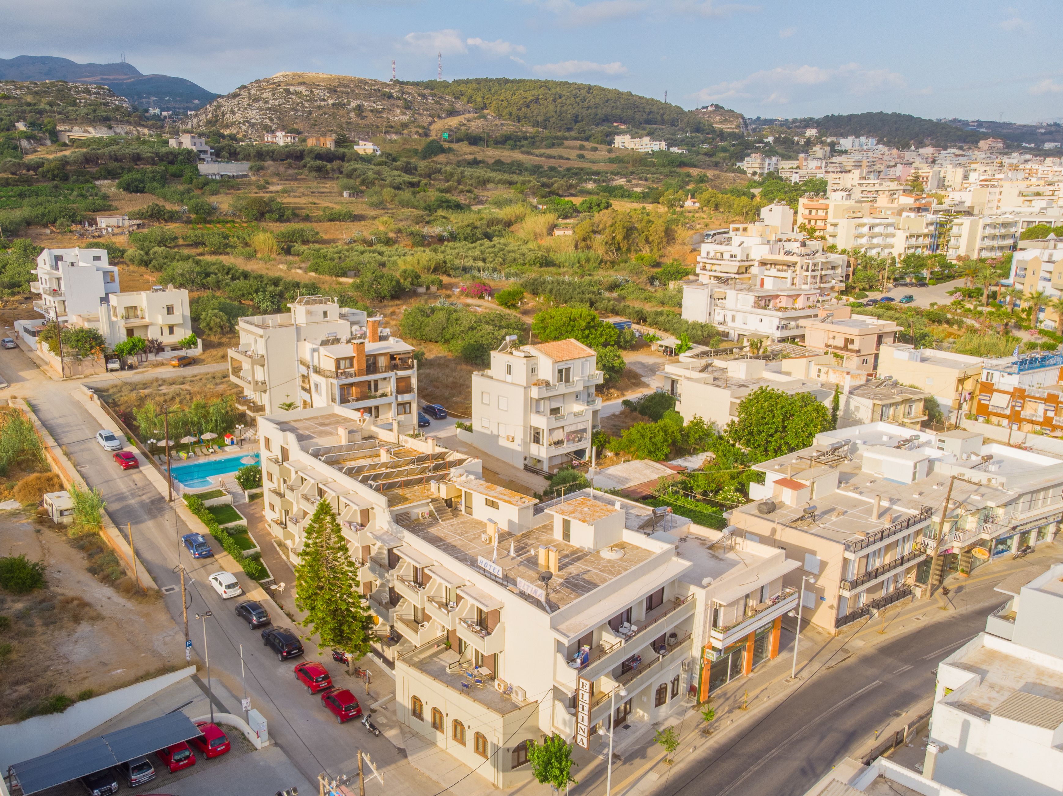 Un hotel con piscina sul tetto, diversi piani e vista sul paese e le colline circostanti.