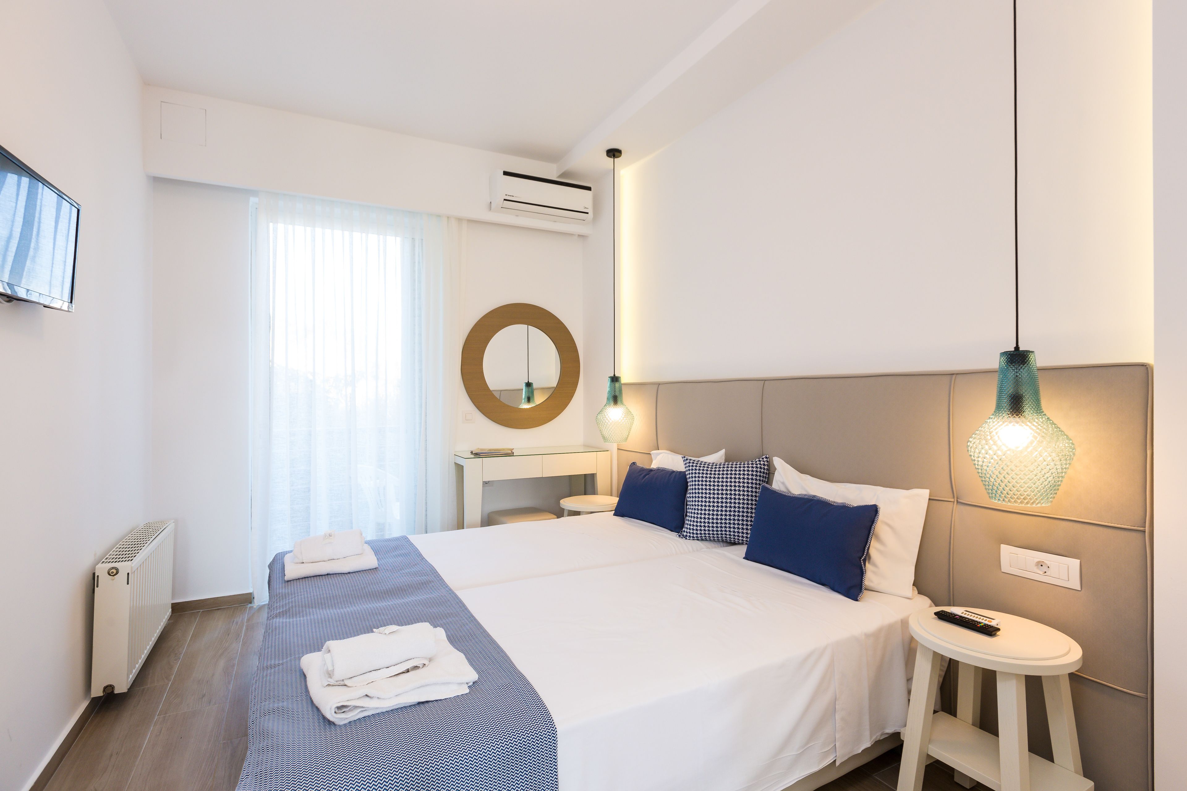 A hotel room with a large bed, bedside table, and a TV mounted on the wall.