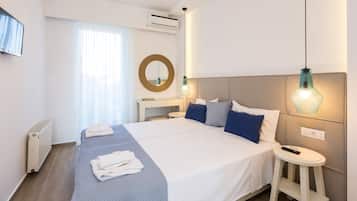 A hotel room with a large bed, bedside table, and a TV mounted on the wall.