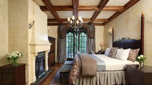 A spacious bedroom with a large bed, a fireplace, and a chandelier.