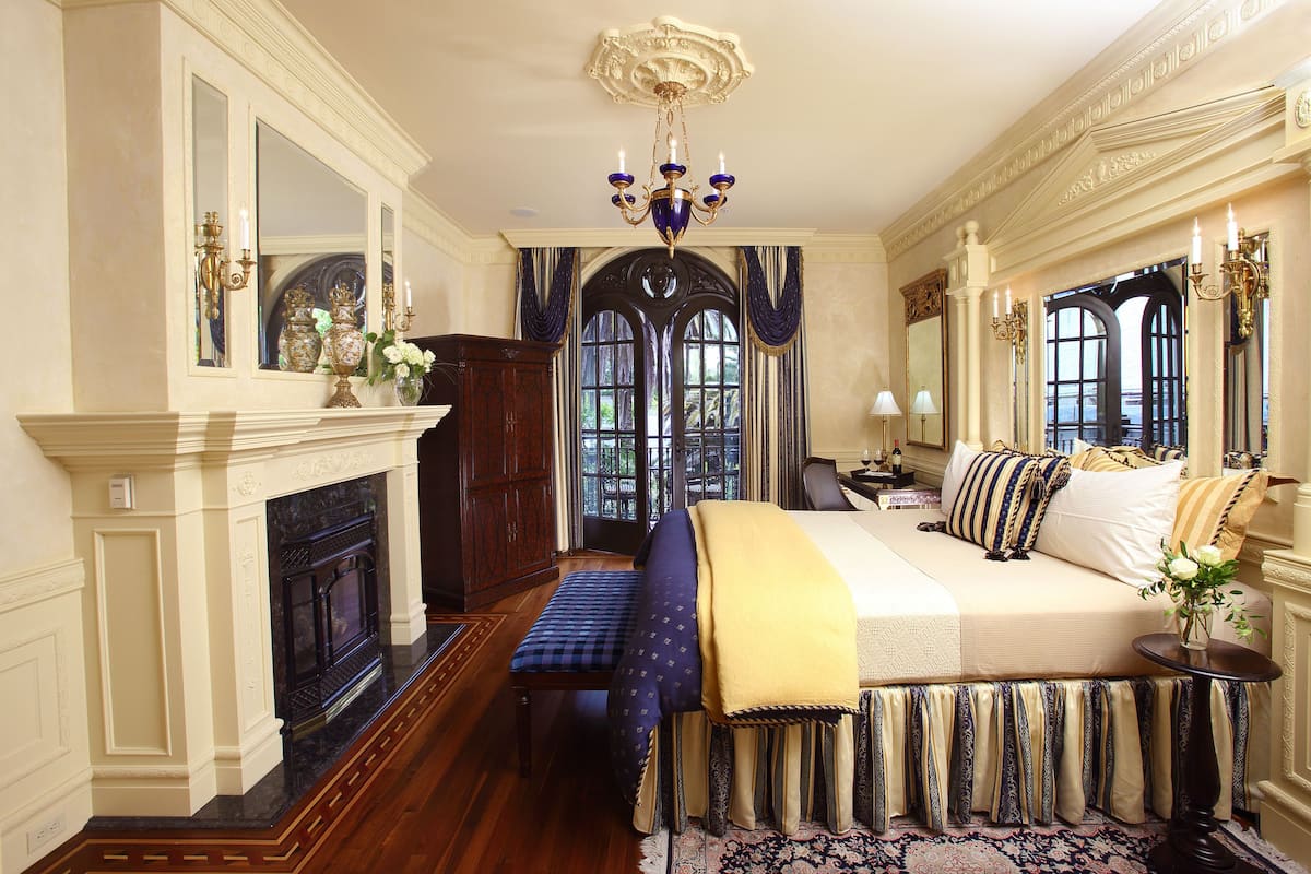 A luxurious bedroom with a large bed, a fireplace, and a view through a window.
