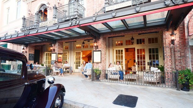The exterior of the Ledson Hotel with a classic brick facade, a balcony with ornate railings, and a vintage car parked in front.