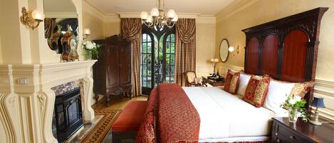 A spacious bedroom with a large bed, a fireplace, and a view of the outdoors.