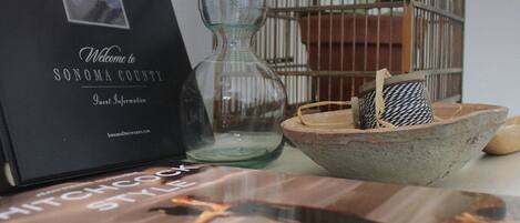Une enseigne accueillante pour le comté de Sonoma, une carafe en verre, un panier tressé et un livre intitulé « Le style Hitchcock ».