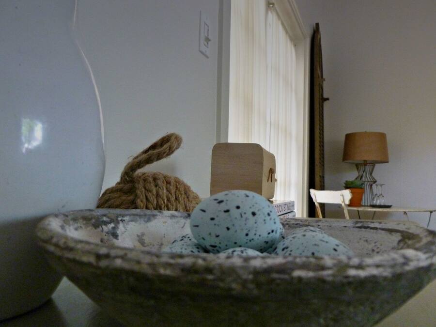 A rustic interior with a stone bowl containing eggs, a rope, and a wooden box.