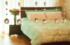 A bedroom with a bed, a hanging chandelier, and a vase with flowers. - Dream Castle (Seogwipo)