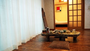 Une pièce traditionnelle avec un sol recouvert de tatamis, une petite table en bois et un ensemble à thé, ainsi qu’une porte coulissante en papier de riz (shoji).