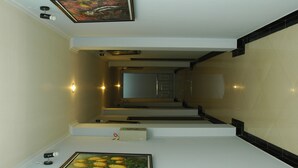 A modern interior with a staircase, a framed picture on the wall, and a small table with a device. - Hotel Unik (Bandung)