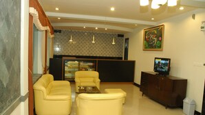A lobby with a seating area, a television, and a patterned wall. - Hotel Unik (Bandung)