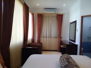Hotelkamer met een bed, bureau, stoel, spiegel en douche.
