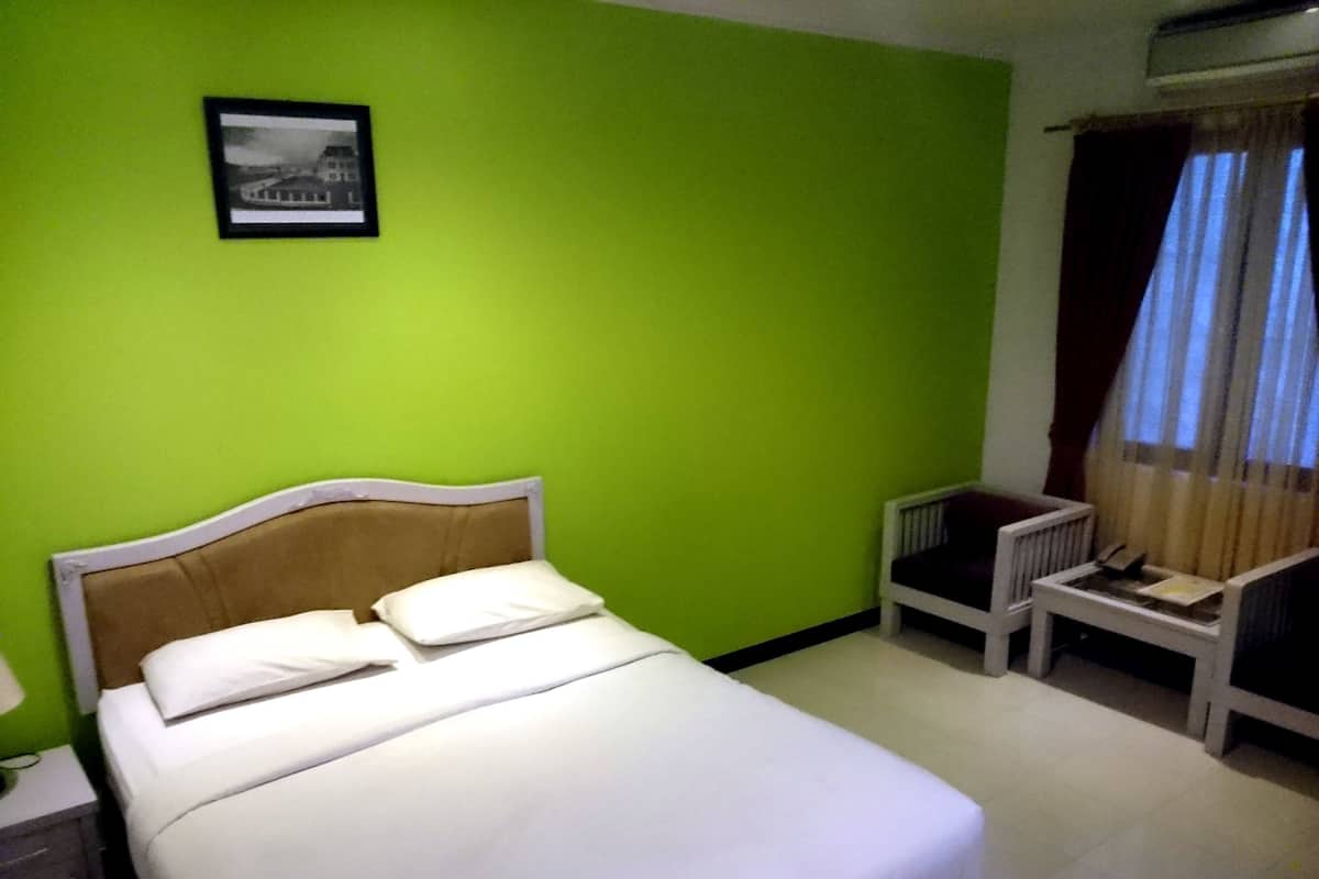 A room with a bed, a chair, a nightstand, and a picture on the wall.
