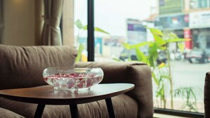 Un cuenco de vidrio transparente con flores secas sobre una mesa de madera en una habitación con un ventanal grande.
