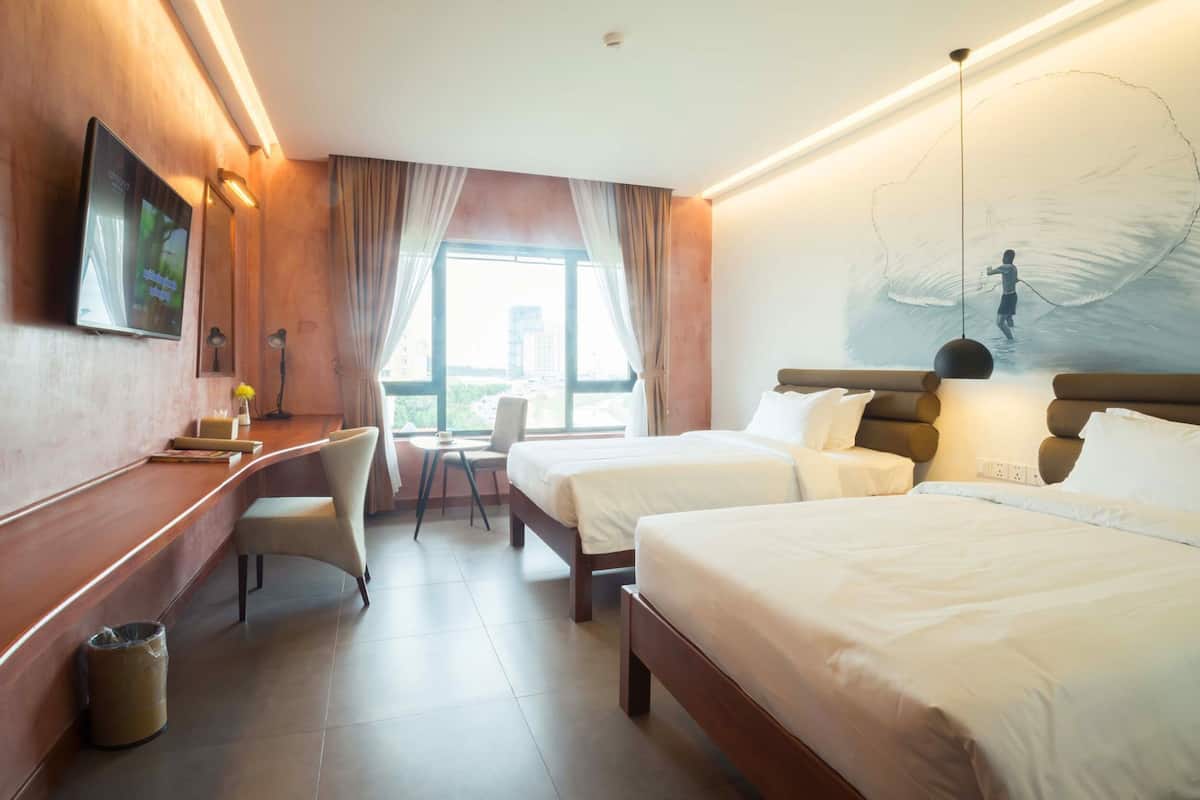 Een hotelkamer met een bureau, twee bedden, een televisie en een groot raam.