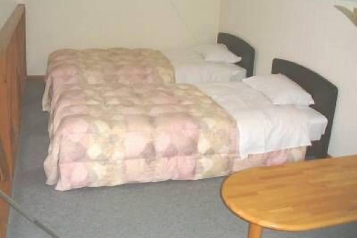 Un petit logement composé d’une seule pièce, comprenant un lit, une table de chevet et une chaise.