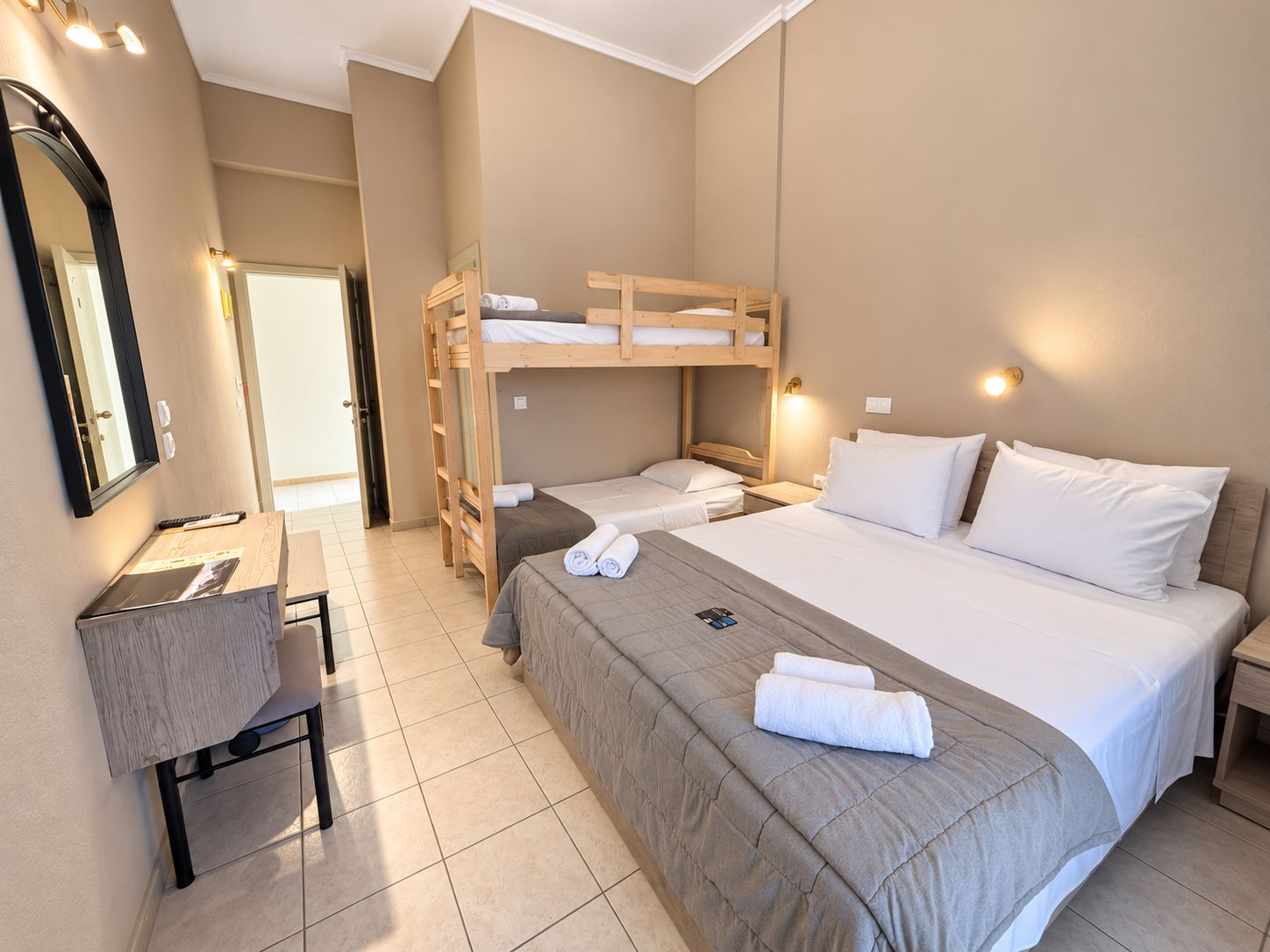 A hotel room with bunk beds, a desk, and a chair.