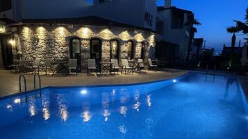 Un hotel con piscina, paredes de piedra y sillones de descanso.