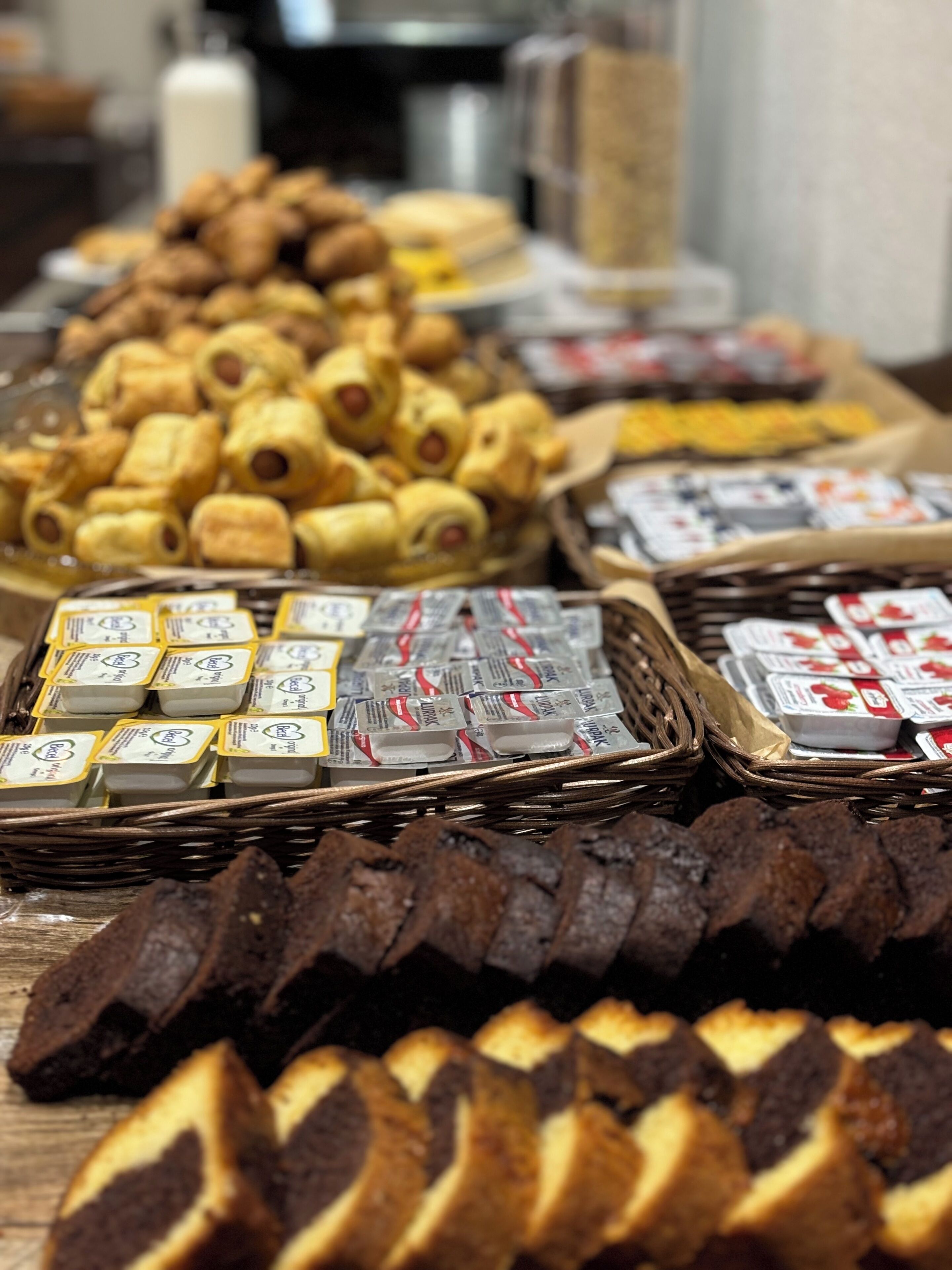 A buffet table with various food items including pastries, sandwiches, and packaged goods.