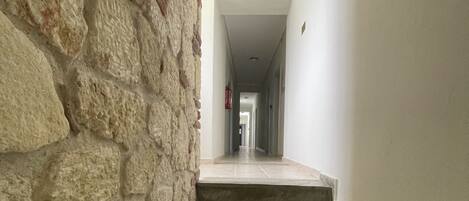 A stone staircase leading to a landing with a white wall and a door at the end.