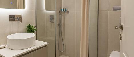 A modern bathroom with a glass-enclosed shower, a white sink, and a toilet.