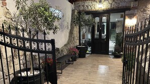A courtyard with a wooden floor, a black wrought iron gate, potted plants, and a bench. - Samel Hotel (Kassandra)