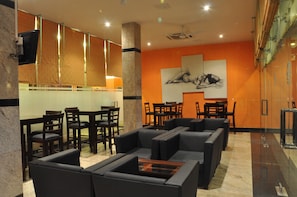 Una hall d'albergo con un'area salotto, una reception e un grande quadro appeso al muro.