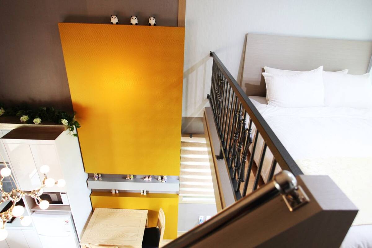 A hotel room with a bed, a desk with a chair, and a staircase.