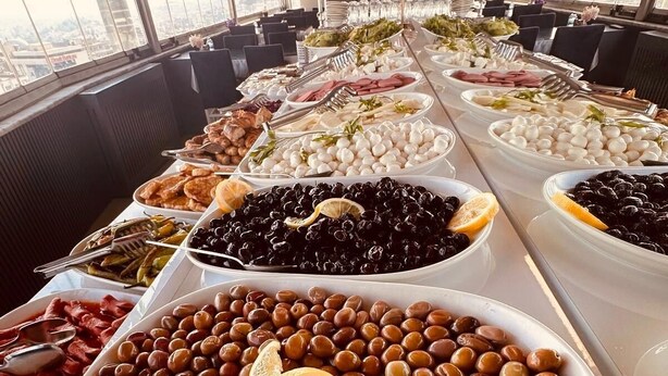 Un bufé con diversos alimentos, entre ellos aceitunas, quesos y carnes.