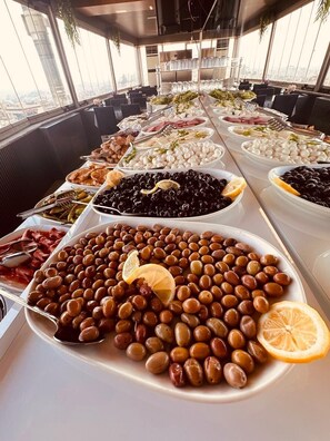 Un bufé con diversos alimentos, entre ellos aceitunas, quesos y carnes.