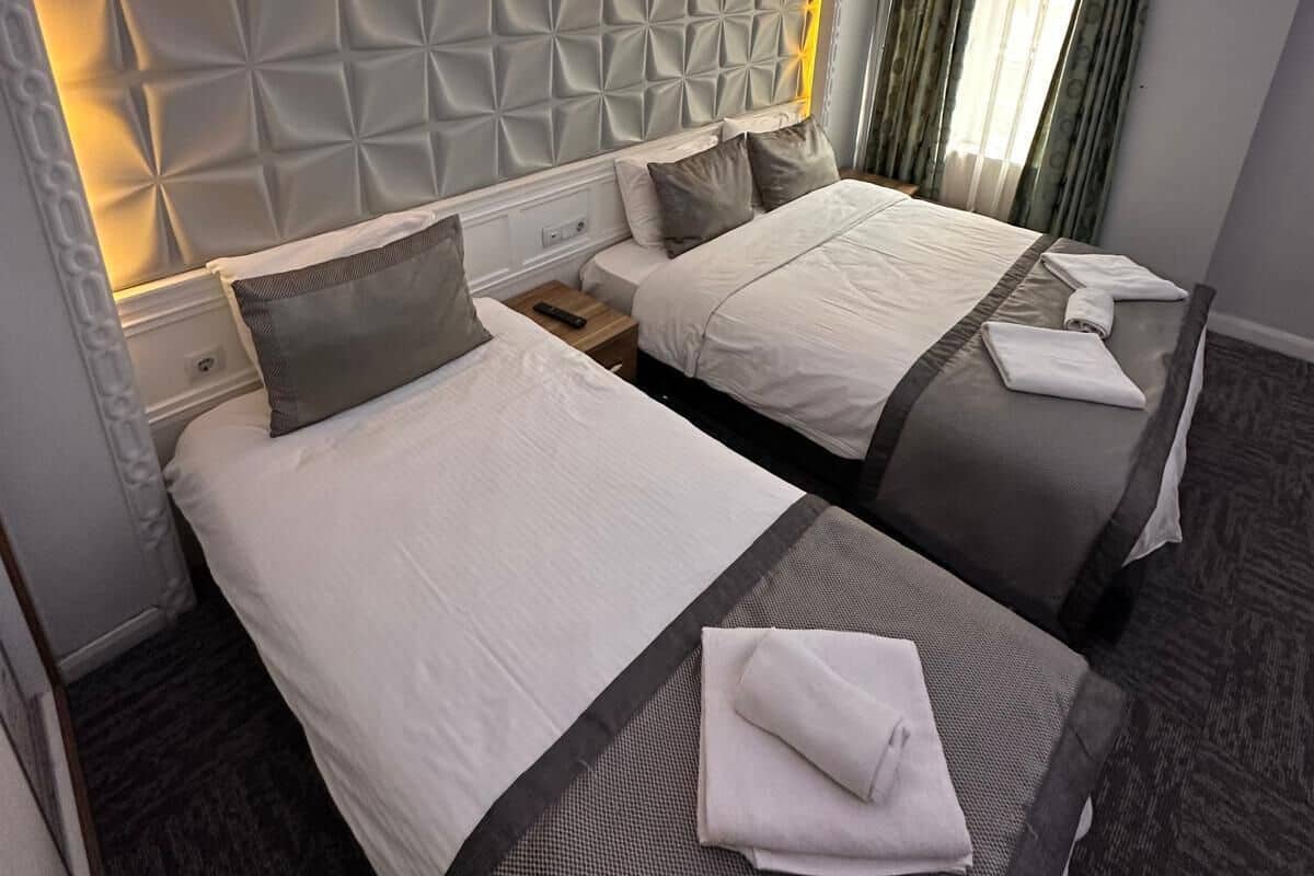 A hotel room with two beds, a modern headboard, and a nightstand.