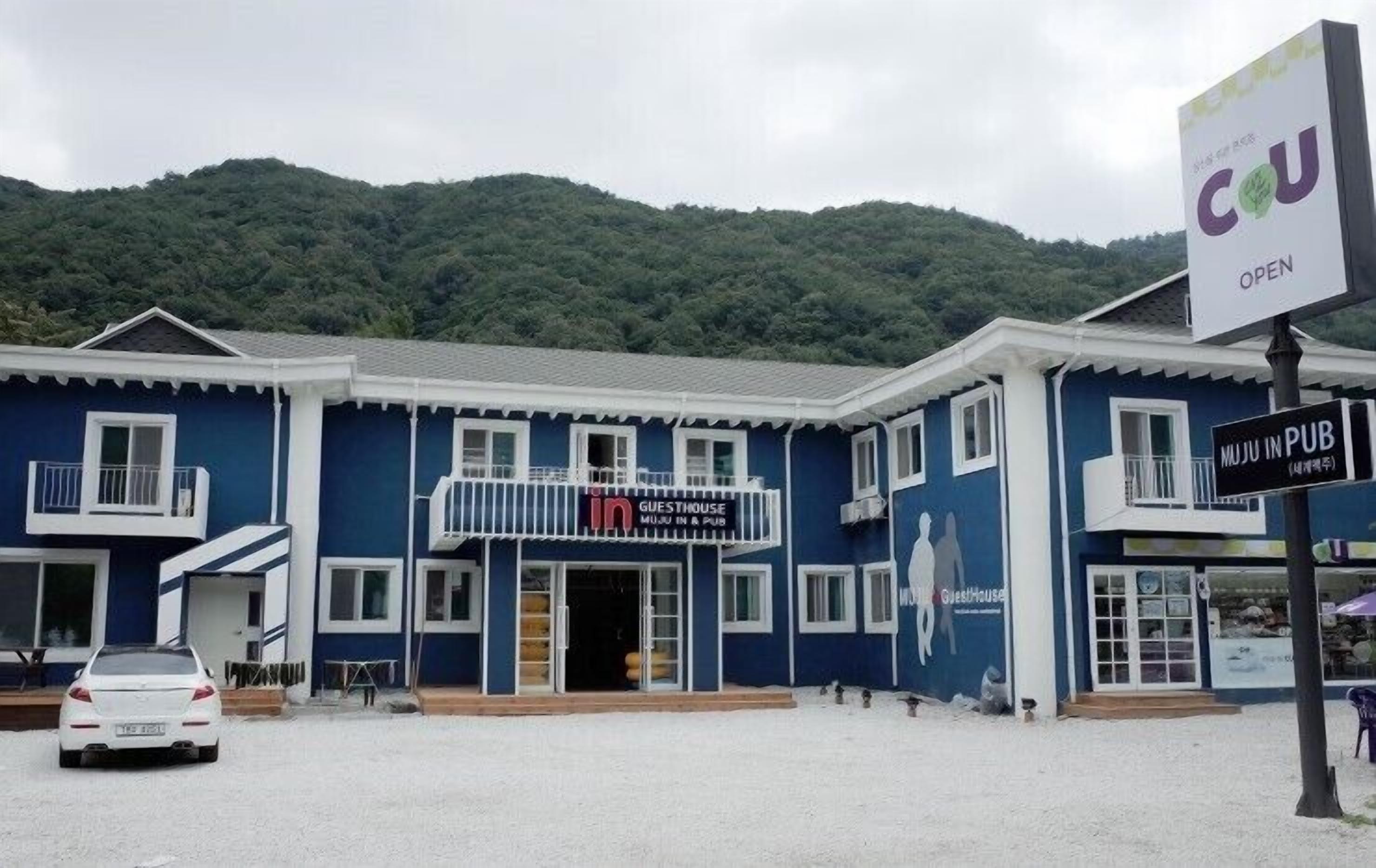 Una casa de huéspedes con un cartel que dice "MUJU IN PUB" y "GUESTHOUSE MUJU IN A PUB".