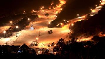 A snow-covered ski slope at night with artificial lighting.