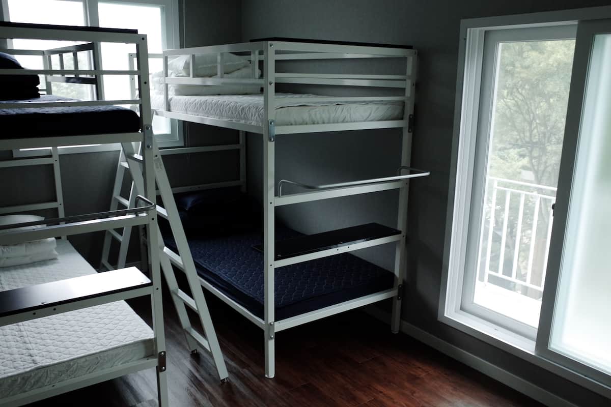 A bunk bed room with a window and a wooden floor.