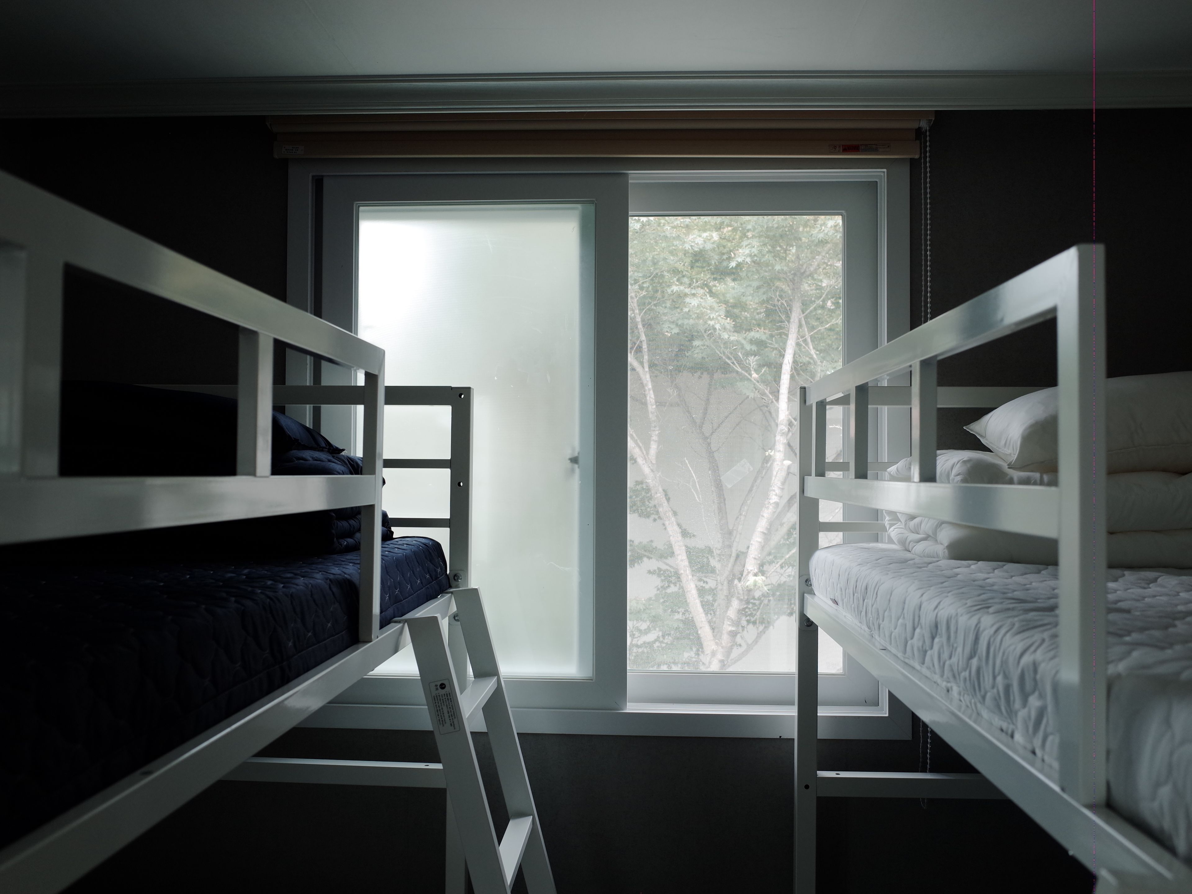 A room with two bunk beds, a sliding glass door to a balcony, and a view of trees outside.