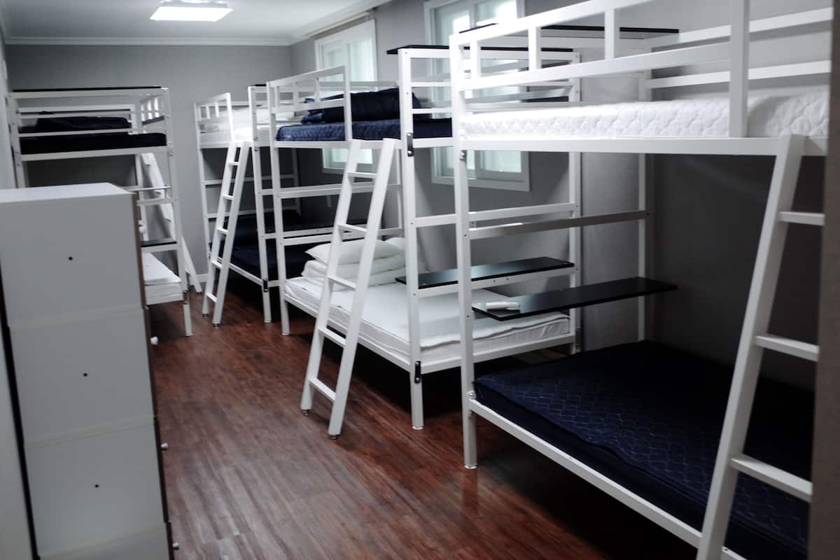 Bunk beds in a dormitory room with wooden flooring and white walls.