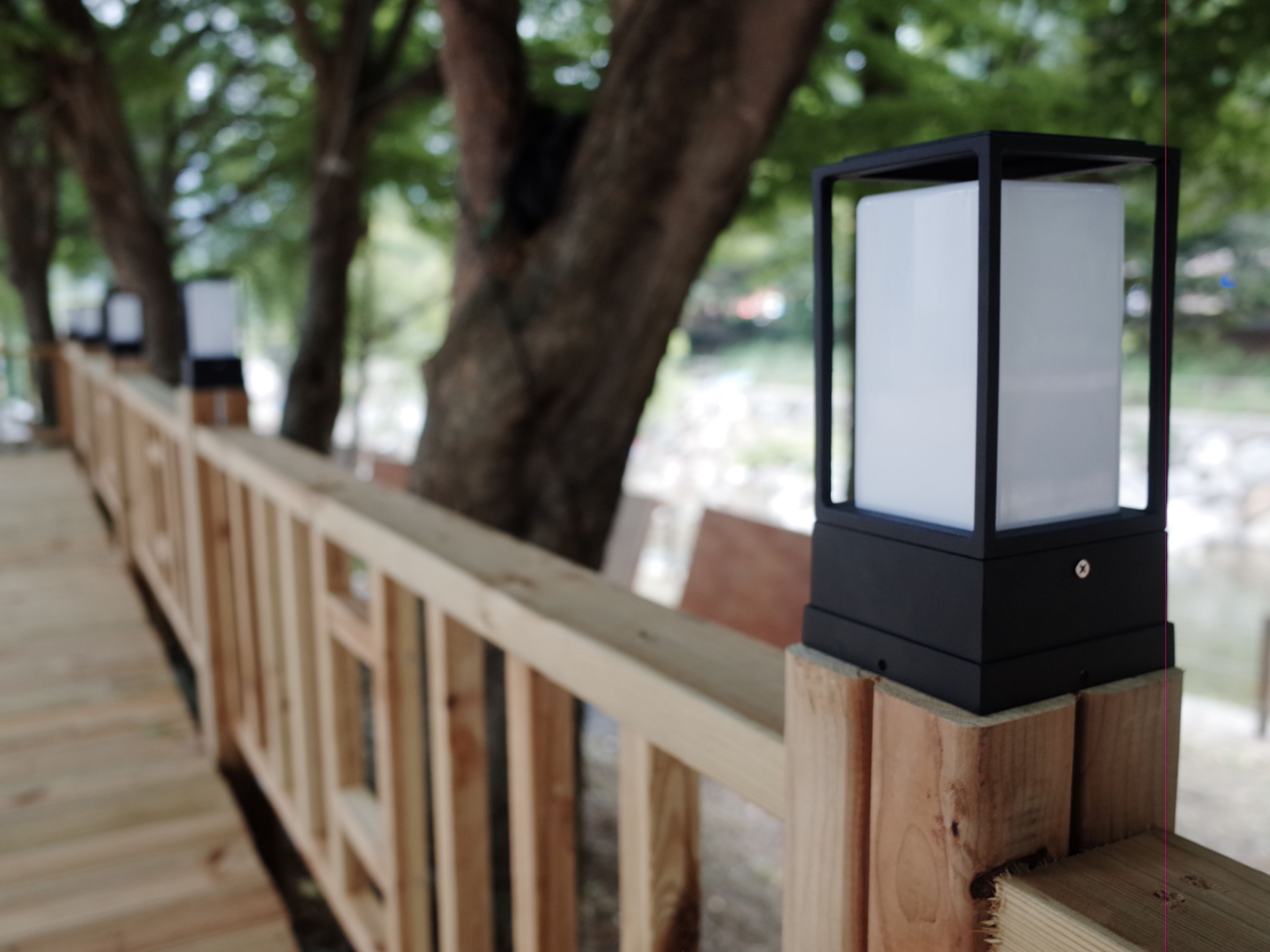 Une terrasse en bois dotée d’une rambarde et d’un lampadaire noir.