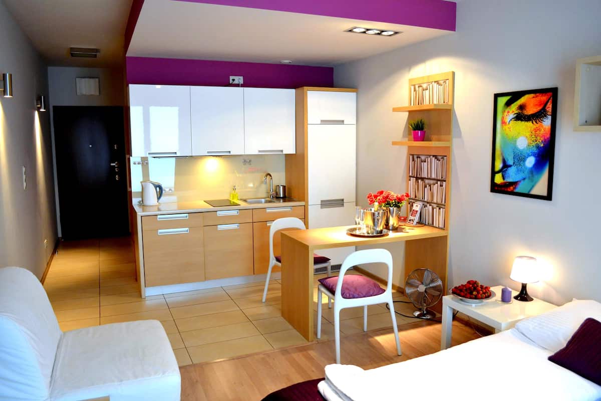 A compact living space with a kitchenette, a dining area, and a bed.