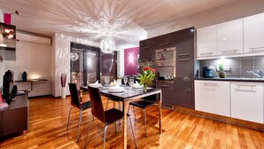 Uma cozinha moderna com piso de madeira, uma mesa de jantar para quatro pessoas e uma luminária decorativa no teto.