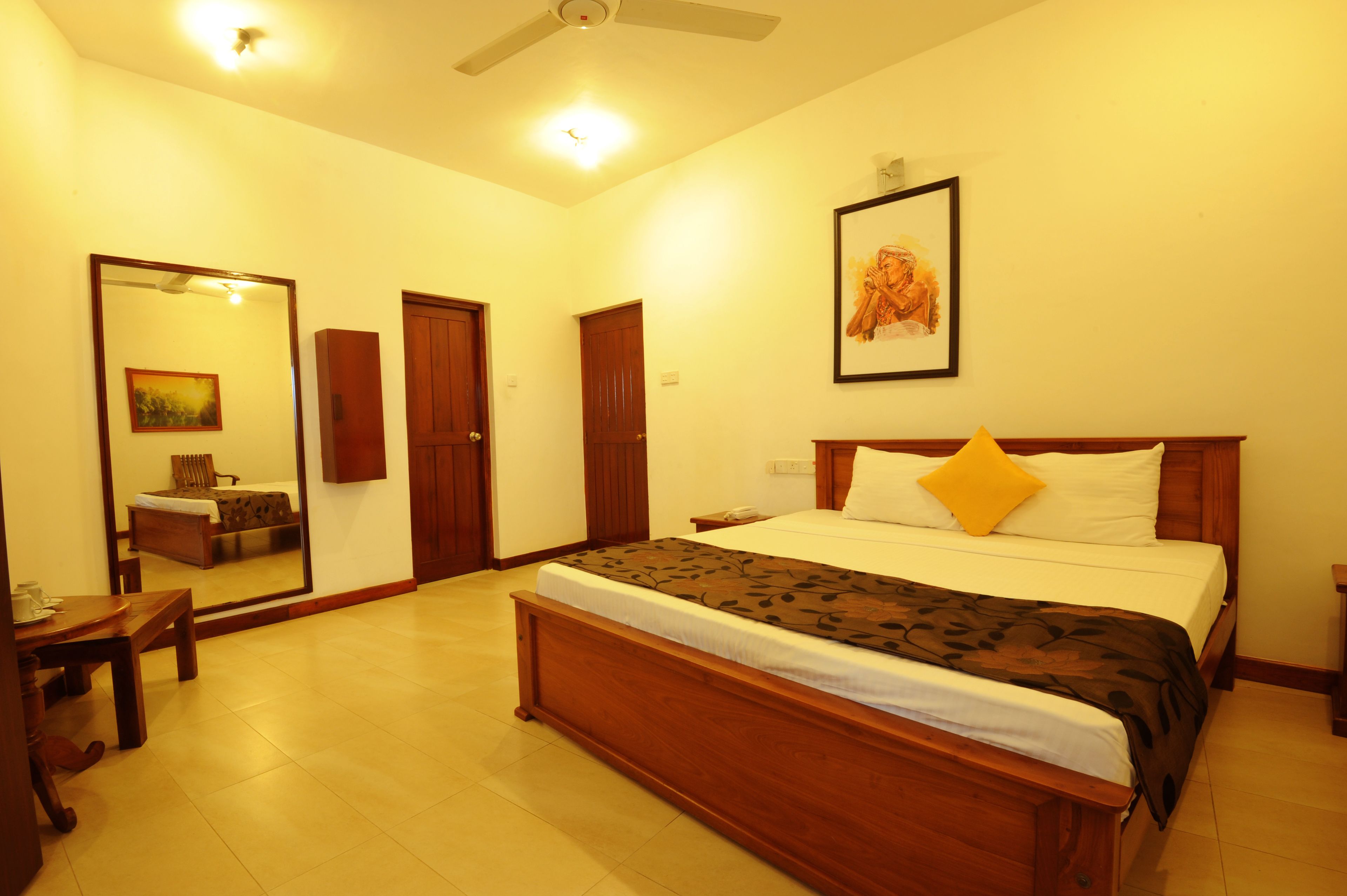 A bedroom with a wooden bed, a bedside table, a chair, a mirror, and a door.
