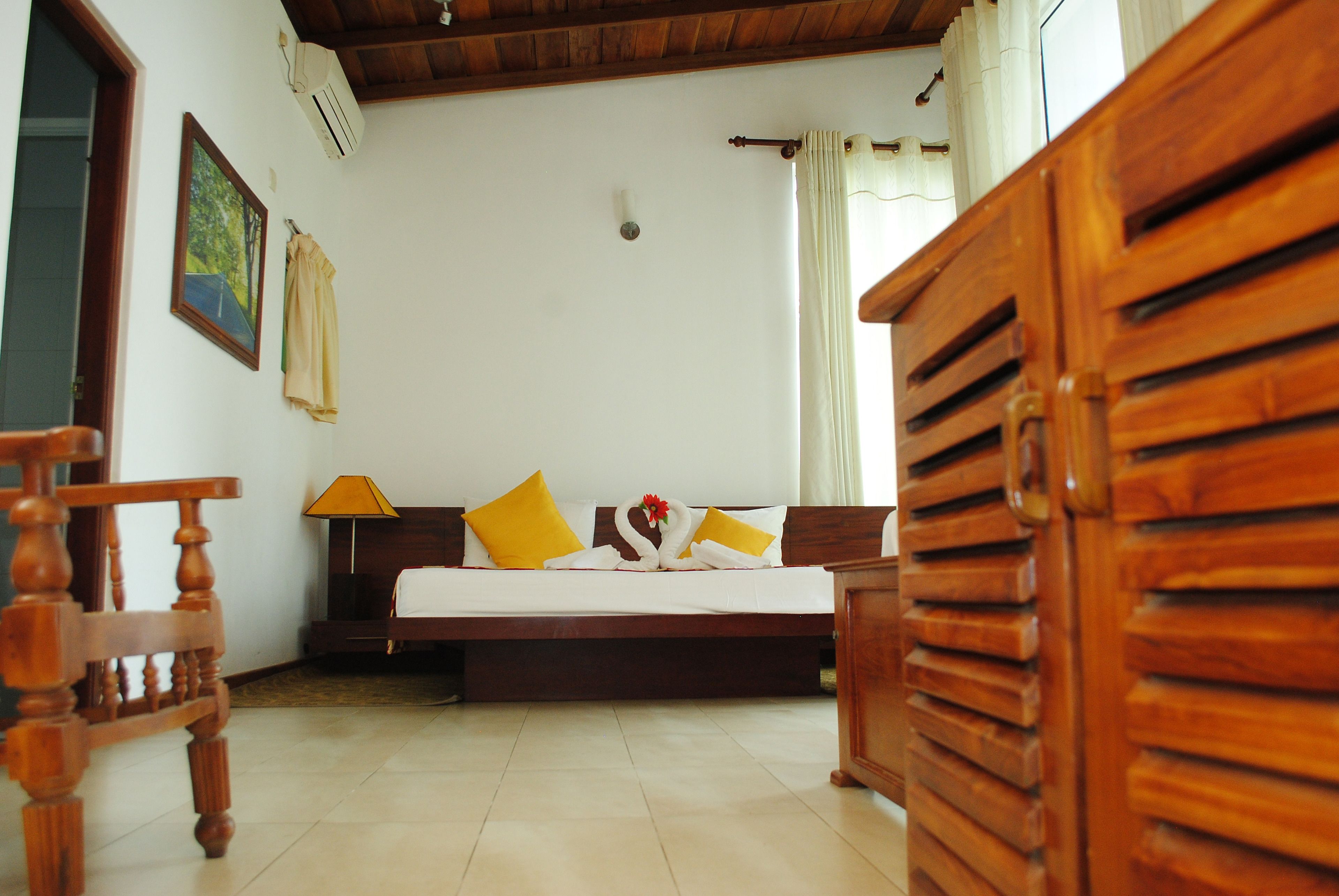 A bedroom with a wooden bed, a nightstand, a chair, and a painting on the wall.