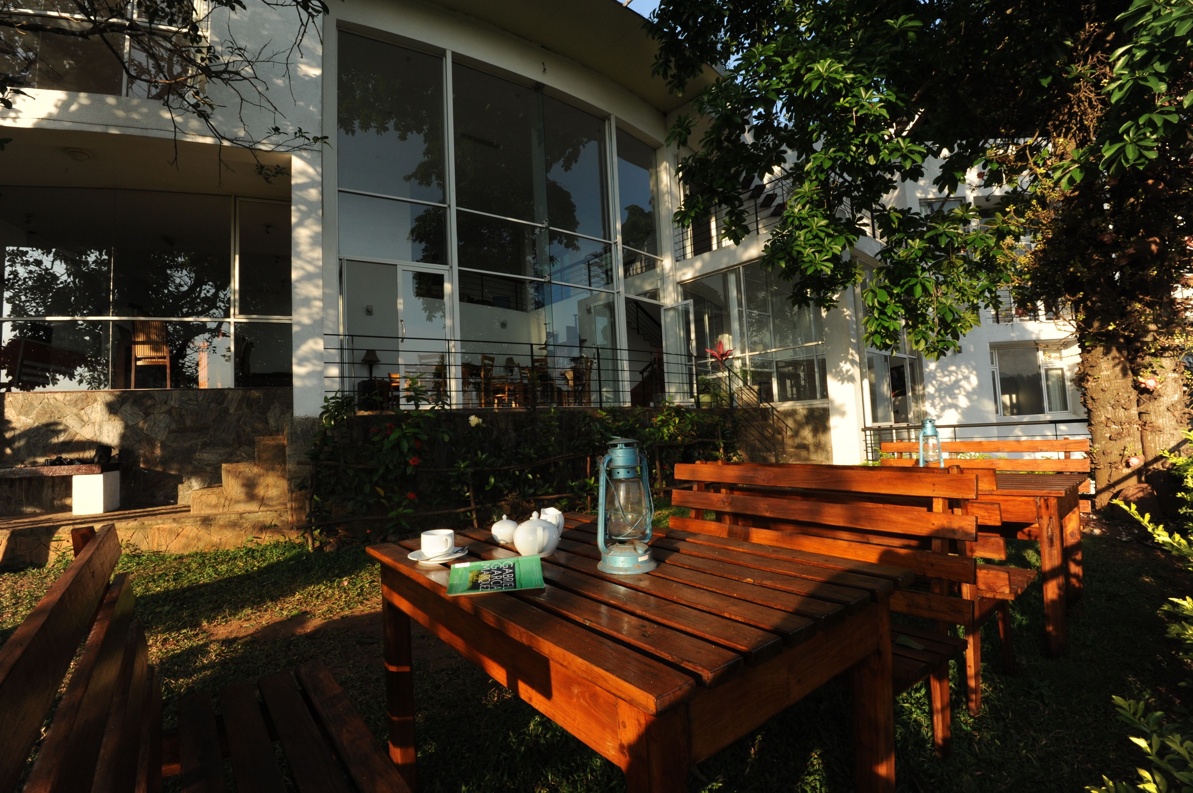 An outdoor seating area with wooden benches and tables, a lantern, and a book.