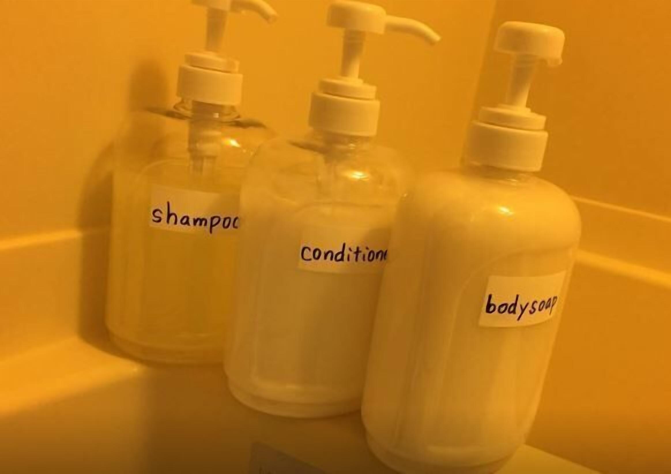 Three bottles of shampoo, conditioner, and body soap on a bathroom counter.