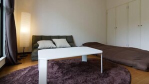 A bedroom with a bed, a sofa, a small table, and a wardrobe. - Sunlife Yamashina Apartment (Kyoto)